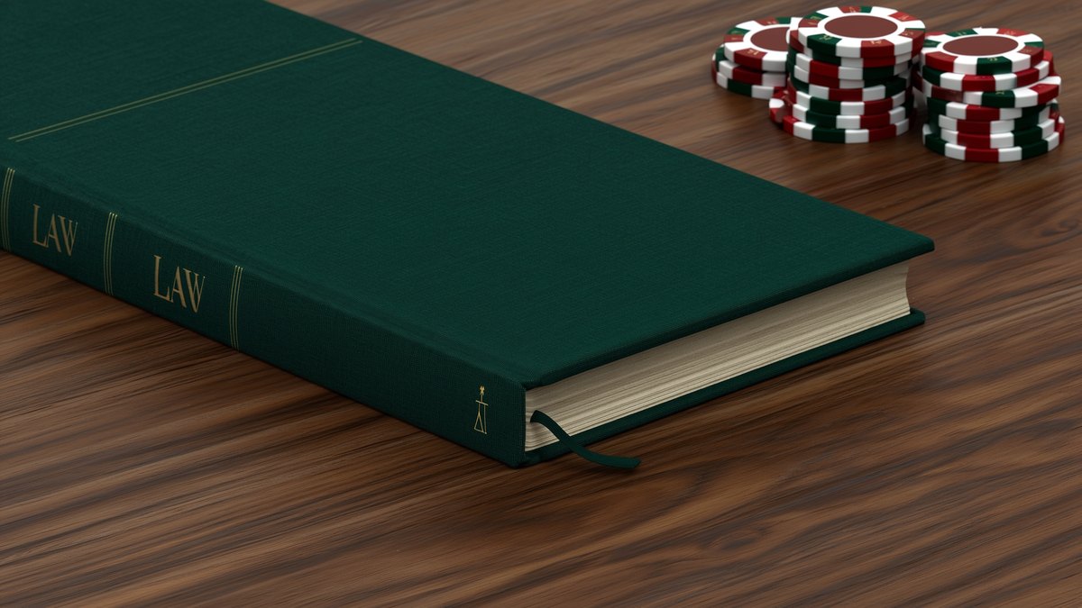 A closed cloth-bound law book on a walnut desk beside a short stack of gaming chips